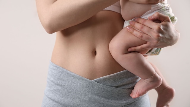 Mujer con su bebé en brazos mostrando la tripa