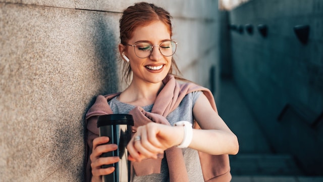 Una chica usando auriculares y un reloj inteligente