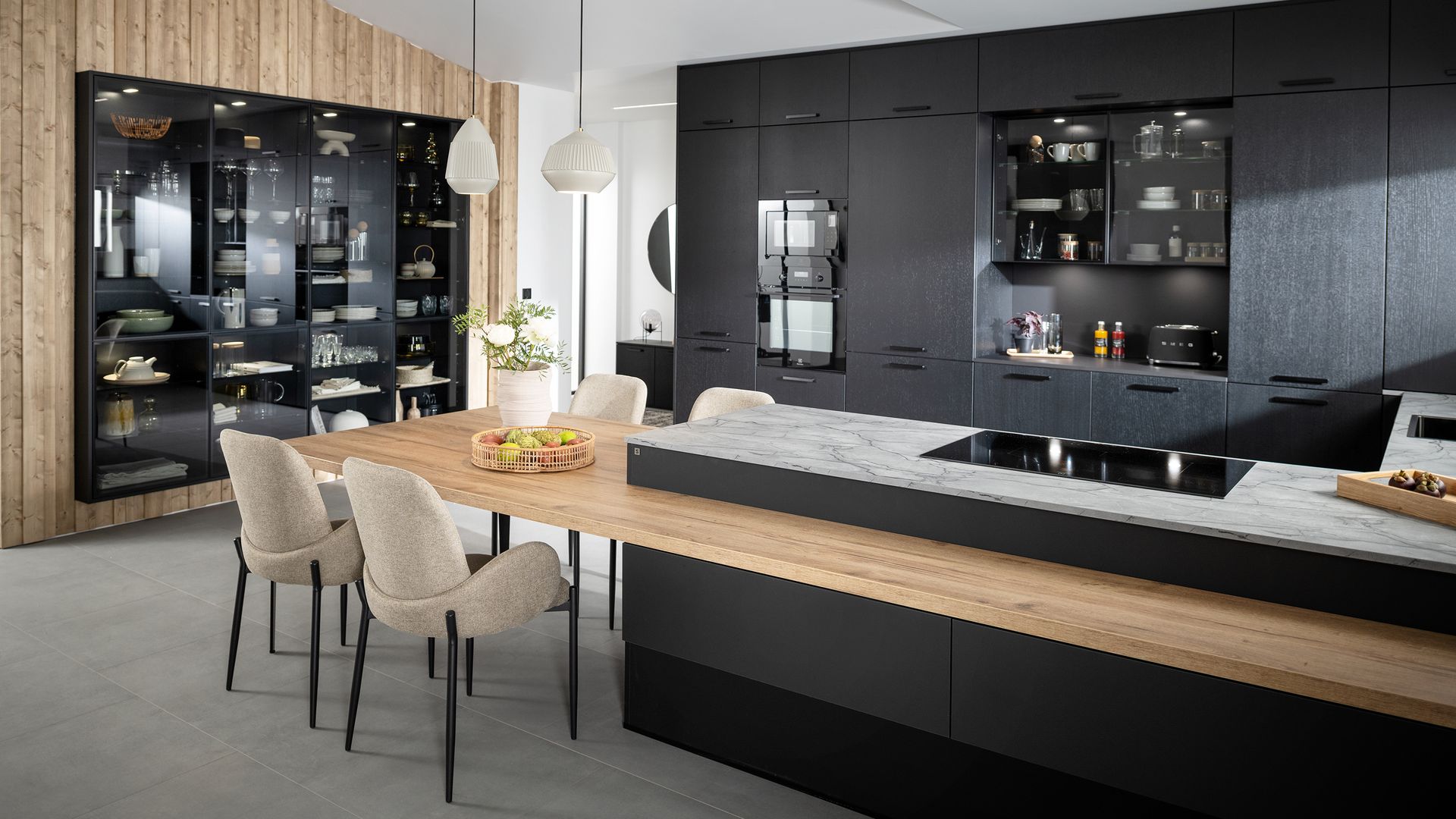 Cocina con muebles negros, vitrina, península de madera con sillas tapizadas