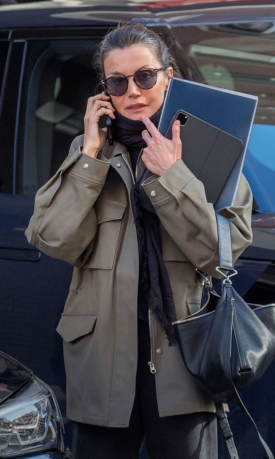 En su última escapada informal a un centro de estética, la Reina lució un 'trench' verde, zapatillas deportivas, bolso negro, bufanda, gafas de sol y un moño alto sujeto con una pinza. Con la mano izquierda, sujetaba un cuaderno grande y una 'tablet'. Con la derecha, su teléfono móvil, por el que no paraba de hablar.