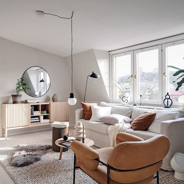 Salón ordenado con sofá blanco y butaca marrón. 